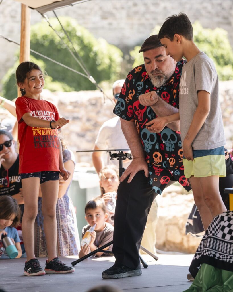Enzo Lorenzo haciendo magia con dos niños voluntarios en el escenario